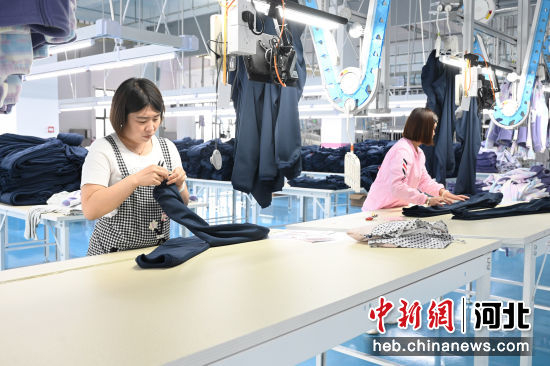 图为工人正在进行服装加工作业。 贾一凡 摄